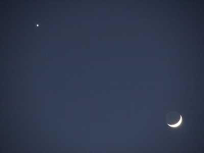 [Venus is a bright white spot in the upper left of the image. The moon is bright in the lower right of the image at less than 25 percent full, but the entire circle of the moon is faintly visible.]